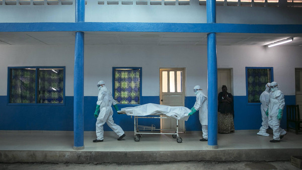 Health workers push a gurney with a dead body at a Red Cross facility in the town of Koidu